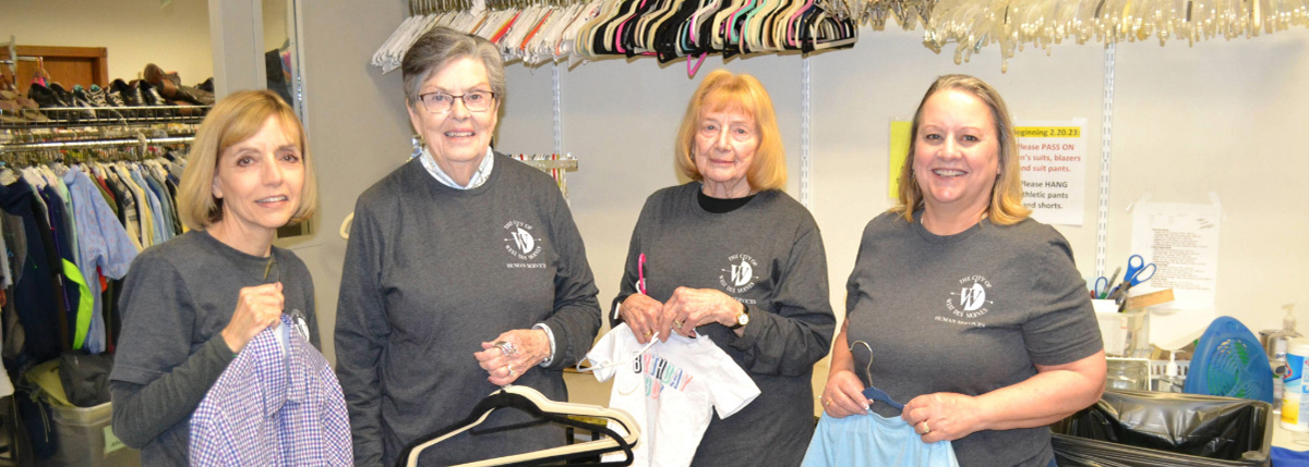 Volunteers in Clothing Closet holding up clothing